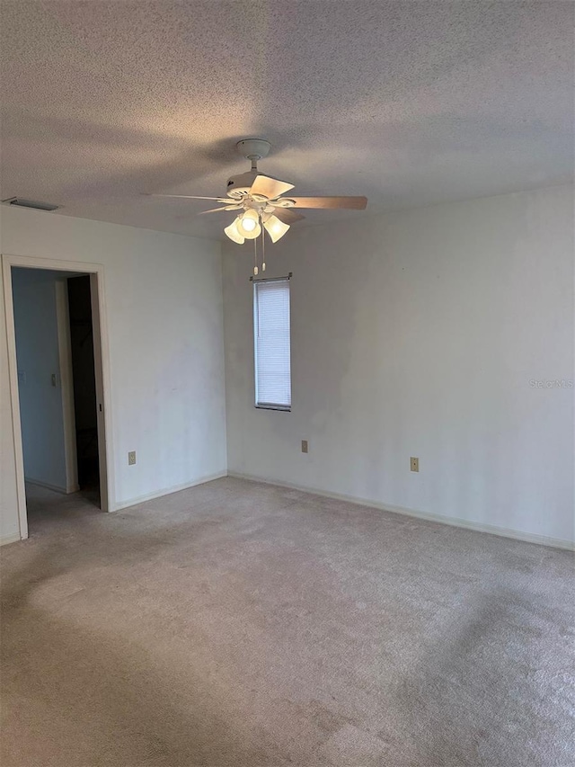 empty room with light carpet, ceiling fan, and a textured ceiling