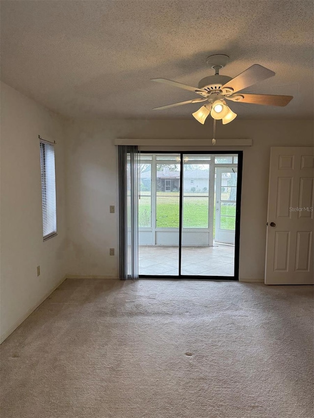 carpeted empty room with ceiling fan and a textured ceiling