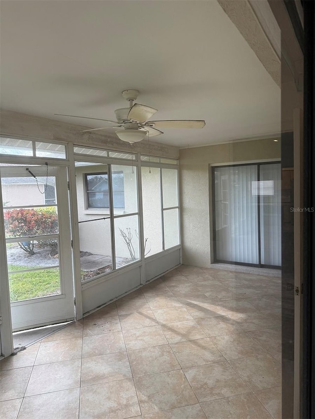 unfurnished sunroom featuring ceiling fan