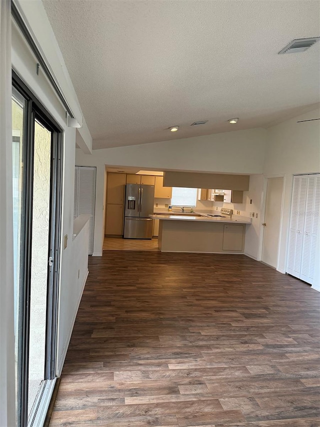 kitchen with stainless steel refrigerator with ice dispenser, dark hardwood / wood-style floors, kitchen peninsula, and a healthy amount of sunlight