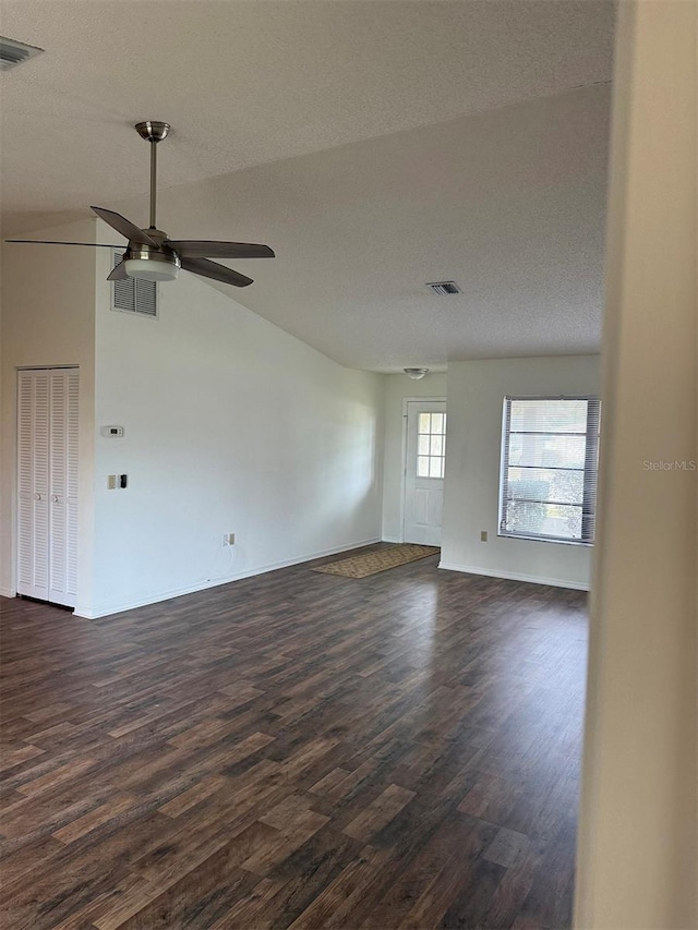 empty room with vaulted ceiling, ceiling fan, a textured ceiling, and dark hardwood / wood-style floors