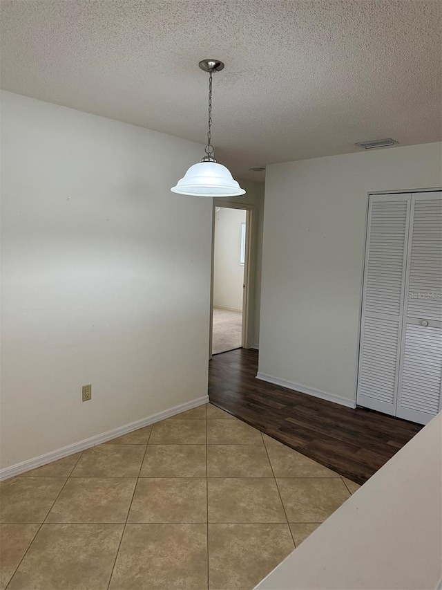 empty room featuring a textured ceiling and light tile patterned floors