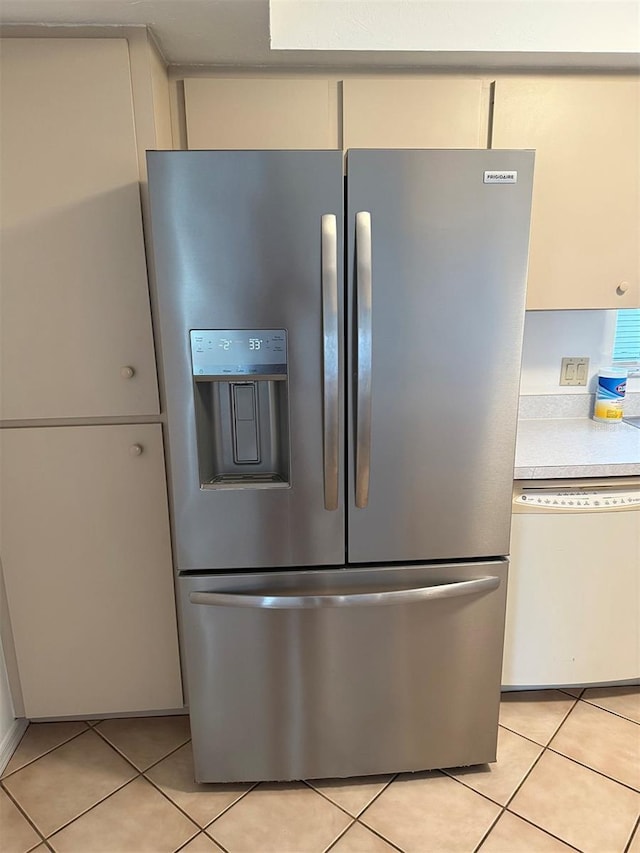 kitchen featuring light tile patterned flooring, white dishwasher, and stainless steel fridge