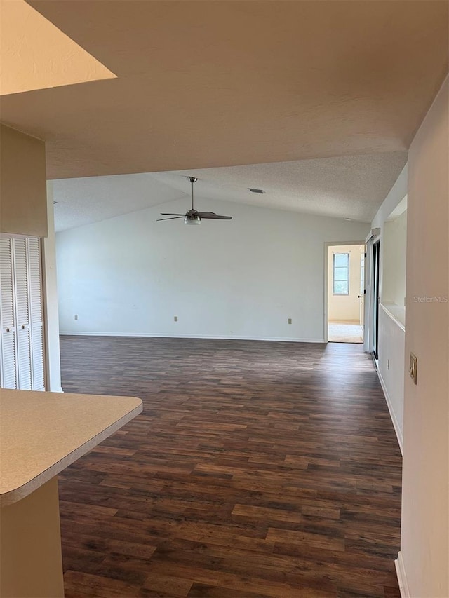 unfurnished living room featuring vaulted ceiling, ceiling fan, and dark hardwood / wood-style floors