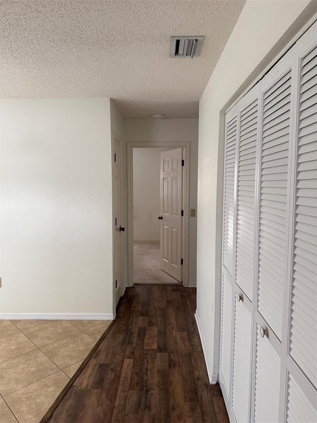 hall with a textured ceiling and wood-type flooring