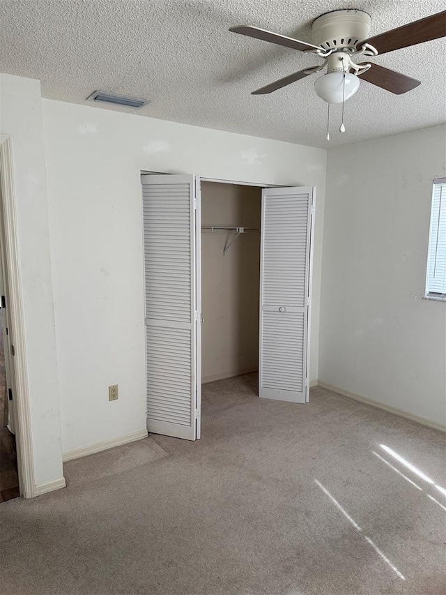 unfurnished bedroom with ceiling fan, light colored carpet, and a textured ceiling