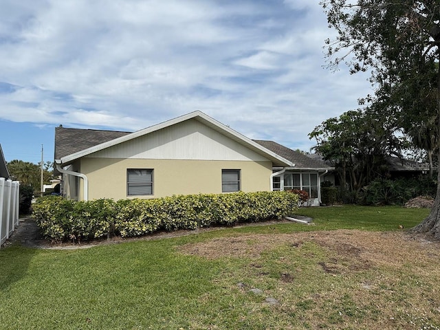 view of property exterior with a lawn and a sunroom