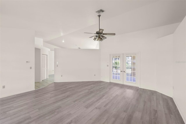 empty room with french doors, ceiling fan, vaulted ceiling, and light wood-type flooring