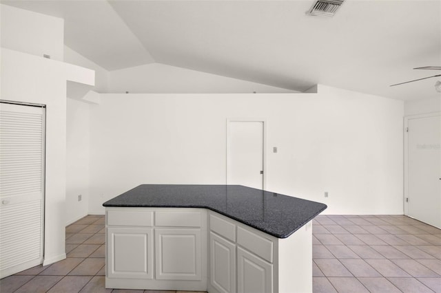 kitchen featuring light tile patterned flooring, a kitchen island, vaulted ceiling, white cabinets, and ceiling fan