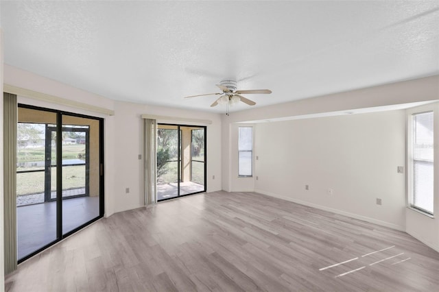 spare room featuring light wood-type flooring, ceiling fan, and a textured ceiling