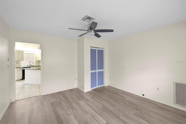 unfurnished room featuring ceiling fan, sink, and light wood-type flooring