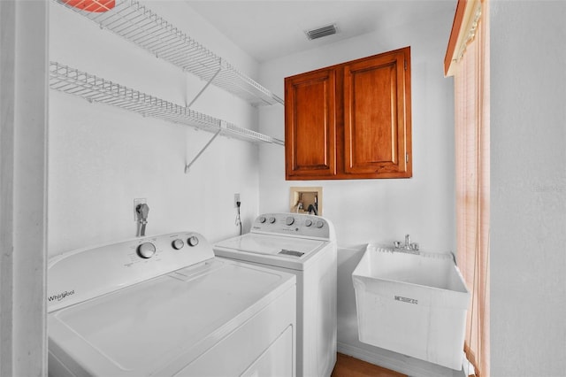 clothes washing area featuring washing machine and dryer, sink, and cabinets