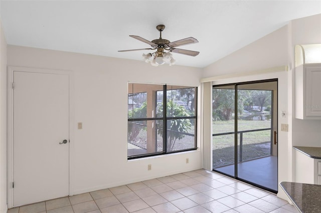 unfurnished room featuring ceiling fan, light tile patterned flooring, and vaulted ceiling