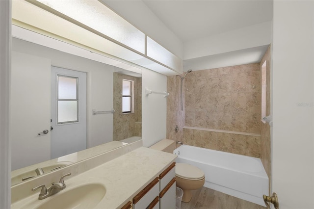 full bathroom with hardwood / wood-style flooring, toilet, vanity, and tiled shower / bath combo