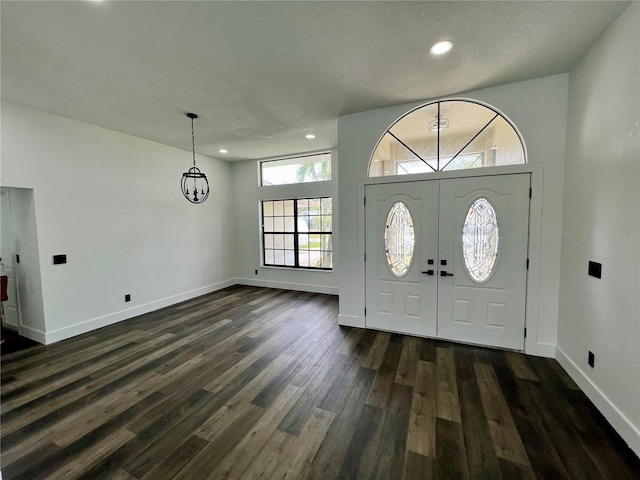 foyer entrance with a chandelier, a textured ceiling, and dark hardwood / wood-style flooring