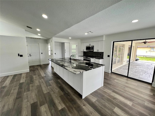 kitchen with white cabinetry, dark hardwood / wood-style flooring, lofted ceiling, and dark stone countertops