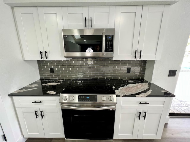 kitchen with dark stone countertops, backsplash, stainless steel appliances, and white cabinets