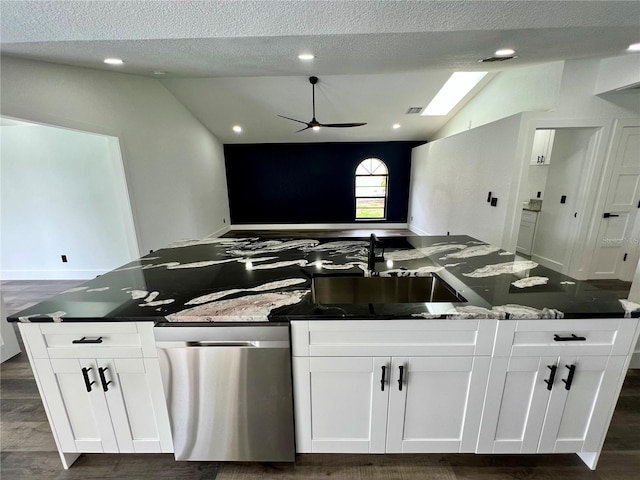 kitchen with ceiling fan, dark wood-type flooring, vaulted ceiling with skylight, and white cabinets