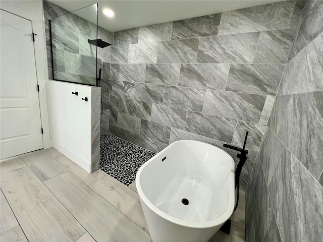 bathroom with tile walls and shower with separate bathtub