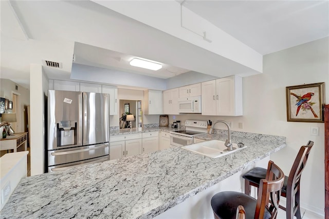 kitchen featuring kitchen peninsula, white cabinets, and white appliances