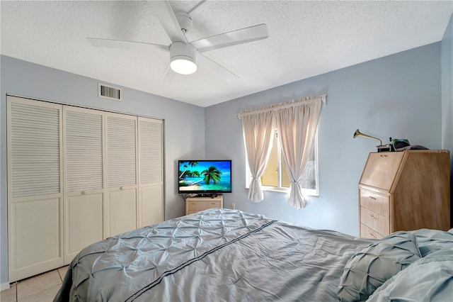 tiled bedroom featuring ceiling fan, a closet, and a textured ceiling