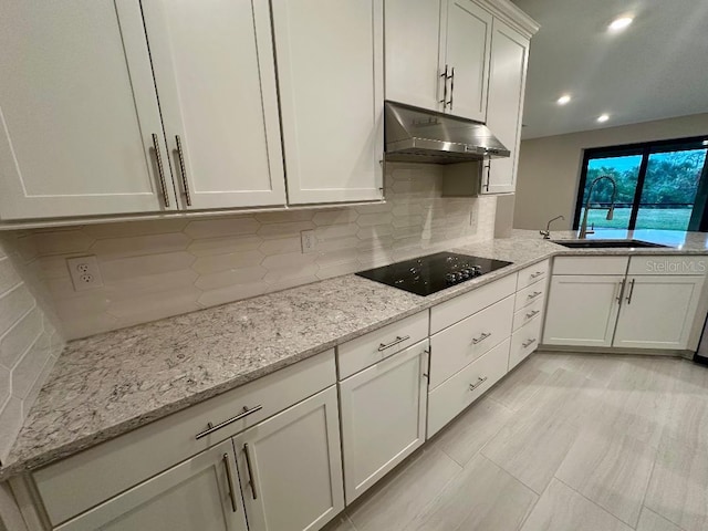 kitchen featuring white cabinetry, decorative backsplash, black electric cooktop, light stone countertops, and sink