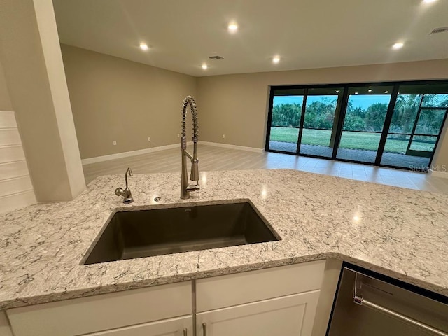 kitchen with dishwasher, white cabinets, light stone countertops, and sink