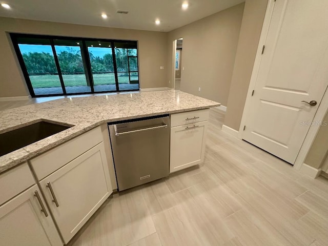 kitchen with light stone counters, white cabinets, and dishwasher