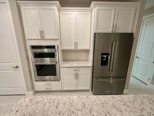 kitchen featuring white cabinets, appliances with stainless steel finishes, and light stone counters