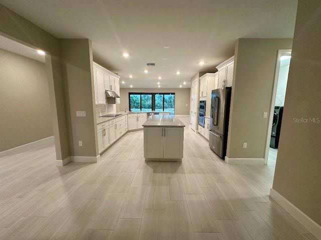 kitchen featuring tasteful backsplash, a center island, high quality fridge, white cabinetry, and black electric cooktop