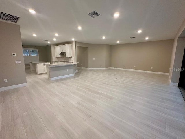 unfurnished living room with light wood-type flooring and sink