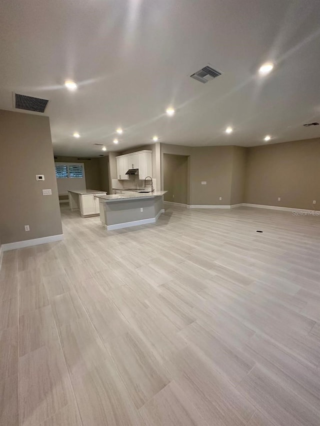 unfurnished living room featuring light hardwood / wood-style flooring and sink