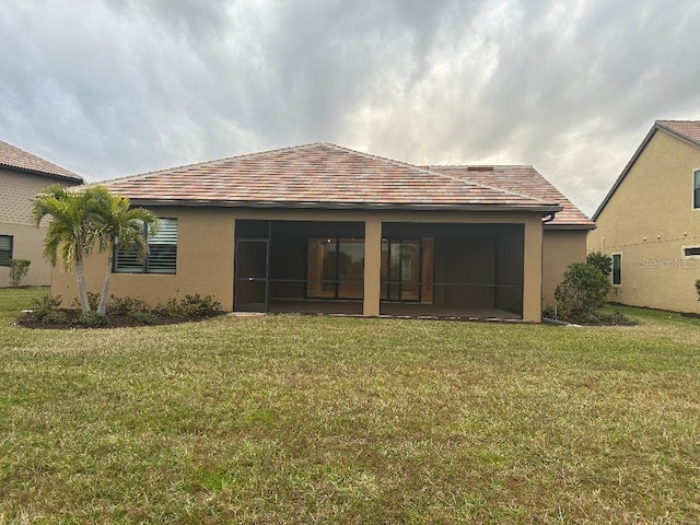 back of house featuring a lawn and a sunroom