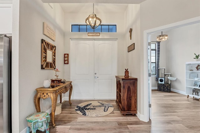 entrance foyer with light hardwood / wood-style floors and a notable chandelier