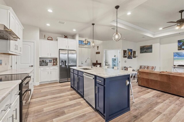 kitchen featuring white cabinetry, a center island with sink, stainless steel appliances, and hanging light fixtures