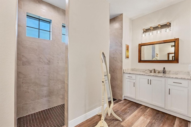 bathroom featuring vanity, wood-type flooring, and a tile shower