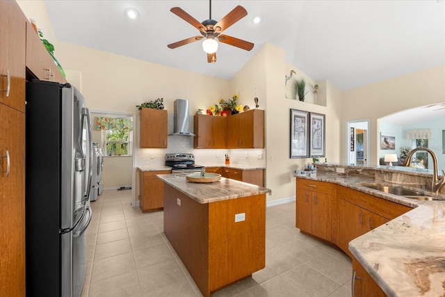 kitchen featuring appliances with stainless steel finishes, washing machine and clothes dryer, sink, a kitchen island, and wall chimney exhaust hood