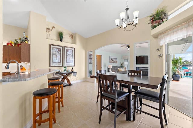 dining area with sink, ceiling fan with notable chandelier, light tile patterned floors, and lofted ceiling