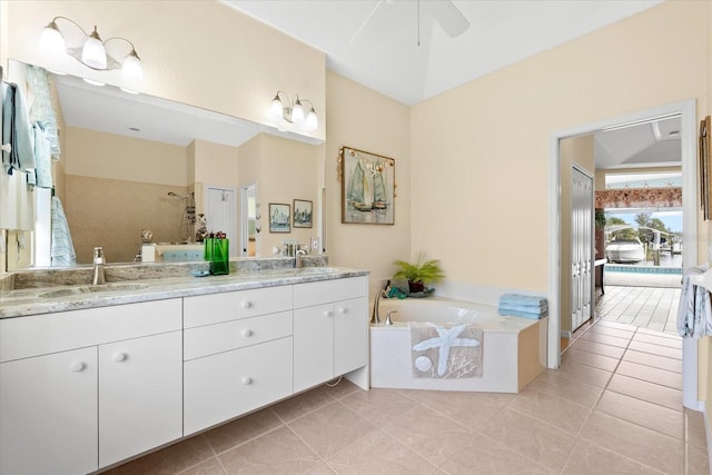 bathroom with tile patterned flooring, a relaxing tiled tub, ceiling fan, and vanity