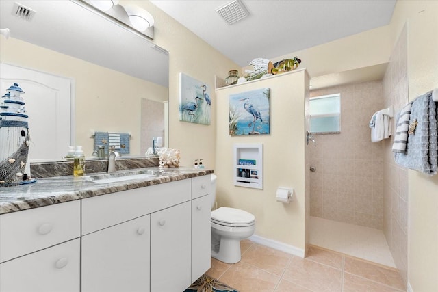 bathroom featuring vanity, toilet, tile patterned floors, and a tile shower