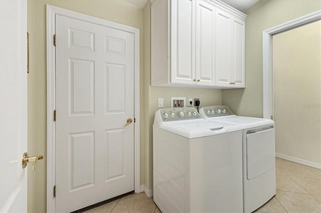 laundry area featuring separate washer and dryer, light tile patterned floors, and cabinets