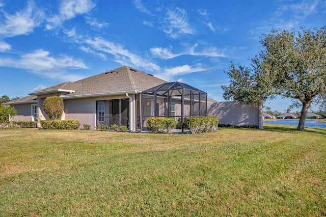 back of house featuring a water view, a lanai, and a lawn