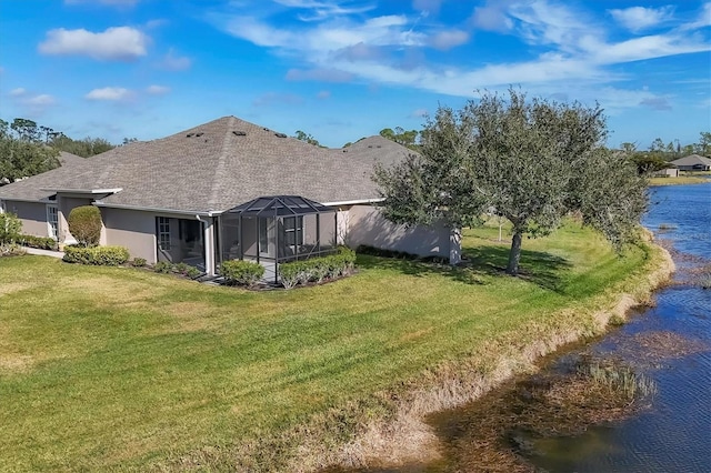 rear view of property featuring a water view, a lanai, and a yard