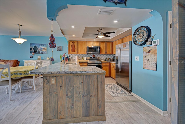 kitchen featuring sink, tasteful backsplash, a raised ceiling, pendant lighting, and stainless steel appliances