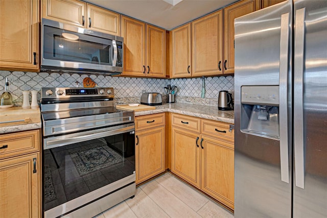 kitchen featuring stainless steel appliances, light stone countertops, light tile patterned floors, and backsplash