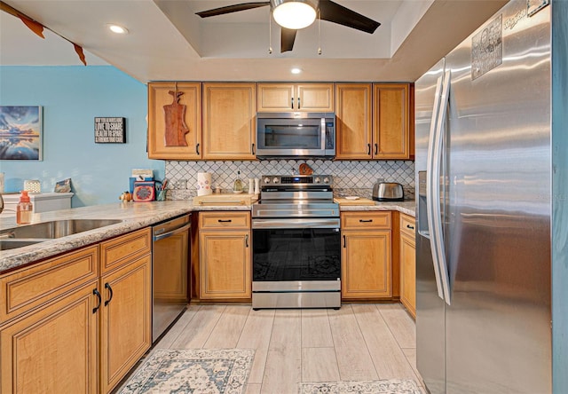 kitchen featuring backsplash, light stone countertops, kitchen peninsula, and appliances with stainless steel finishes