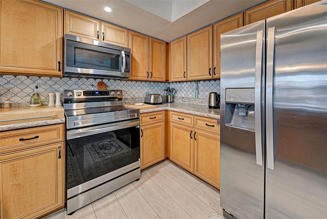 kitchen featuring light stone countertops, appliances with stainless steel finishes, backsplash, and light hardwood / wood-style floors