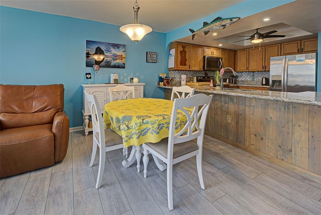 dining room with ceiling fan, sink, and light hardwood / wood-style floors