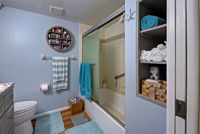 full bathroom featuring bath / shower combo with glass door, hardwood / wood-style floors, vanity, and toilet