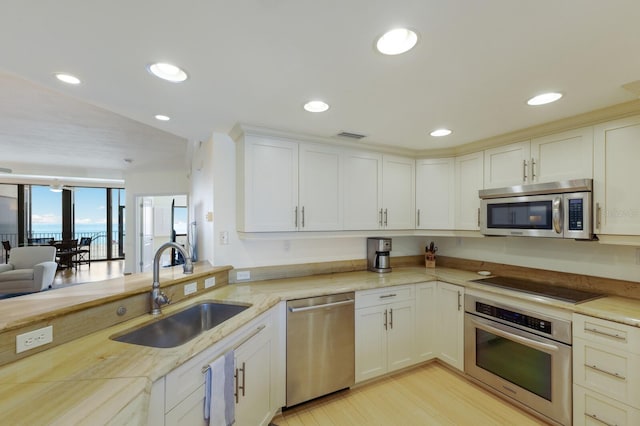 kitchen with white cabinets, sink, stainless steel appliances, and light hardwood / wood-style floors